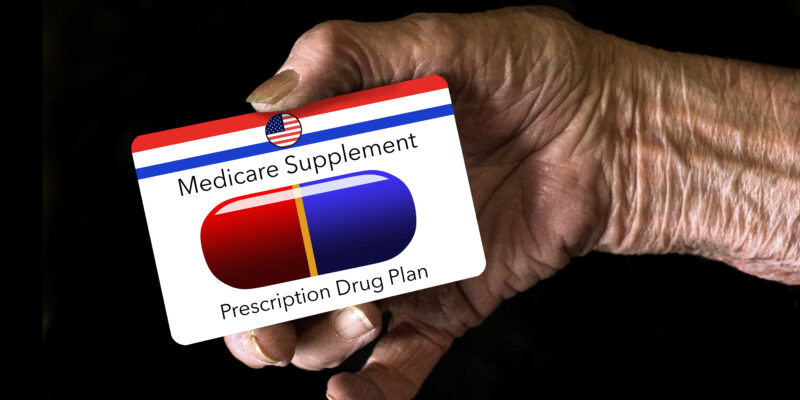 An elderly hand holds a medicare supplement prescription drug insurance