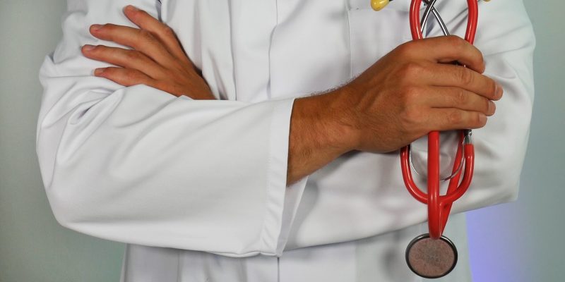 a picture of a doctor on a scrub suit holding a stethoscope. The shot was from neck to waist.